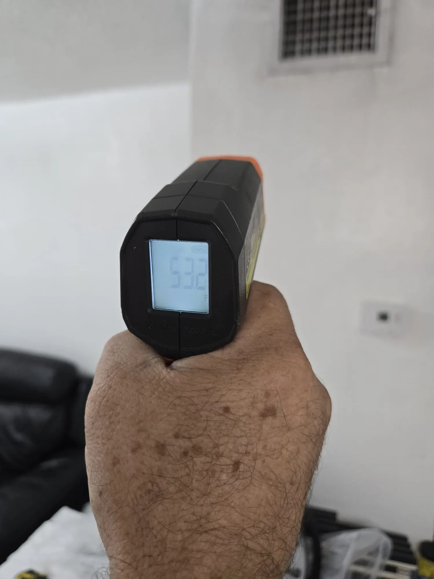 Termómetro infrarrojo midiendo la temperatura de un sistema de ventilación